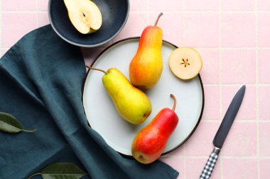 Pembe kaplama üzerinde olgun armutlar olan bir tabak.