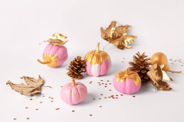 Altın armutla boyanmış balkabakları ve beyaz arka planda yapraklar.