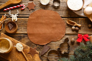 Kahverengi ahşap arka planda Noel kurabiyeleri için taze hamur ve malzemeler.