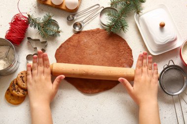 Noel kurabiyeleri için zencefilli ekmeği beyaz arka planda yuvarlayan kadın.