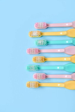 Mavi arka plan üzerinde renkli diş fırçaları.