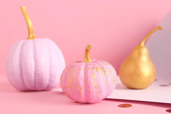 Different painted pumpkins with golden pear on colorful background