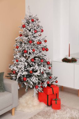 Güzel süslenmiş Noel ağacı ve hediyelerle dolu oturma odasının içinde.