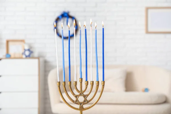 Menorah with burning candles in living room, closeup. Hanukkah celebration