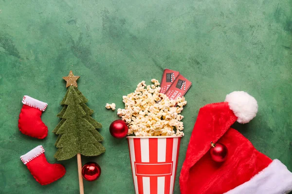 Bucket of popcorn with cinema tickets and Christmas decor on green grunge background