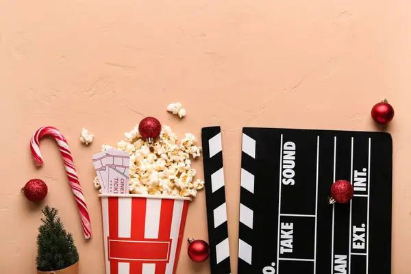 Movie clapper with bucket of popcorn, cinema tickets and Christmas decor on beige grunge background