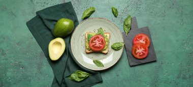 Guacamole soslu lezzetli sandviç ve yeşil arka planda domates.