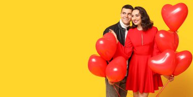 Sarı arka planda kalp şeklinde balonları olan mutlu genç bir çift ve mesaj için yer var. Sevgililer Günü kutlaması