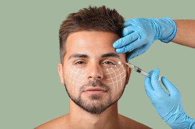 Yeşil arka planda doldurucu enjeksiyon alan yakışıklı bir adam. Cilt bakımı kavramı