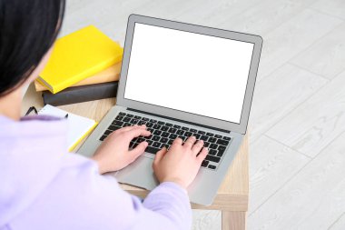 Masada dizüstü bilgisayarla çalışan genç bir kadın.