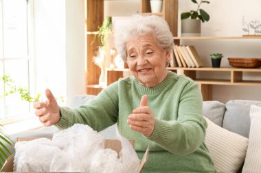 Kıdemli kadın evde paket açıyor.