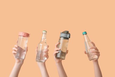 Bej arka planda soğuk su şişeleri olan kadın eller.