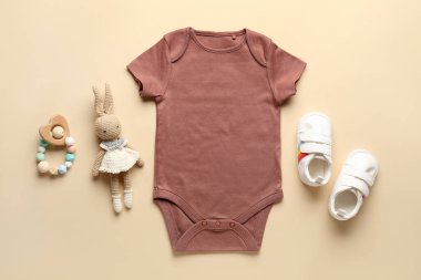 Pamuk bebek kıyafetleri, örgü oyuncaklar ve turuncu arka planda çıngırak.