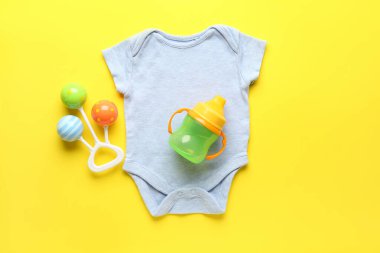 Pamuk elbiseler, bebek şişesi ve sarı arka planda çıngırak.