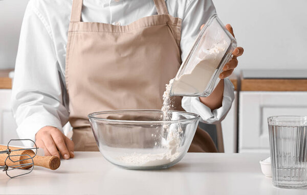 Женщина делает тесто для итальянского гриссини за белым столом на кухне