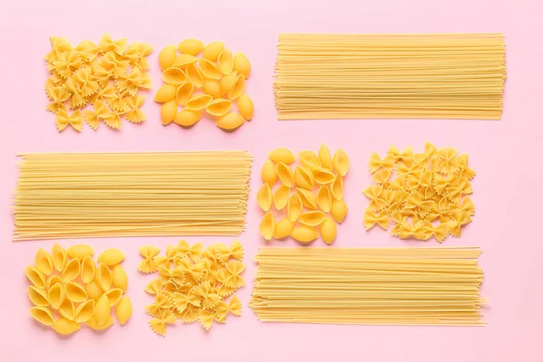 Composition with different uncooked pasta on pink background