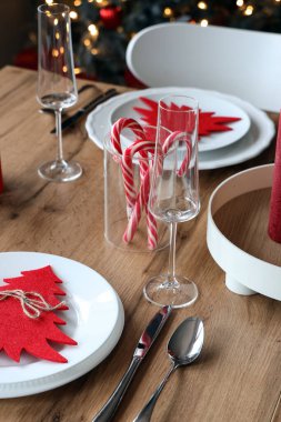 Beyaz tabaklar, çatal bıçak takımı ve Noel süslemeleri ile Noel sofrası