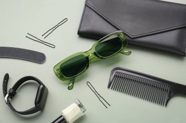 Şık güneş gözlüklü kompozisyon, oje, modern akıllı saat ve yeşil arka planda kadın aksesuarları, yakın plan.