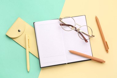 Renkli arkaplan üzerine şık gözlük, defter, kalem ve çanta kompozisyonu