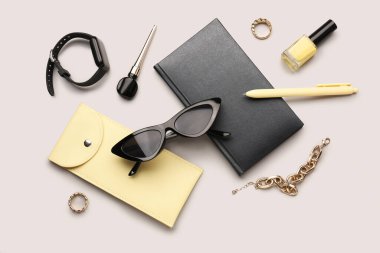 Şık güneş gözlüklü kompozisyon, modern ukala, not defteri ve gri arka planda kadın aksesuarları.
