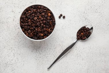 Hafif arkaplanda aromalı kahve çekirdekleri olan kase ve kaşık.