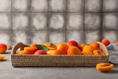 Gri masada tatlı kayısıları olan hasır kutu.