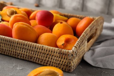 Gri masada tatlı kayısıları olan hasır kutu.