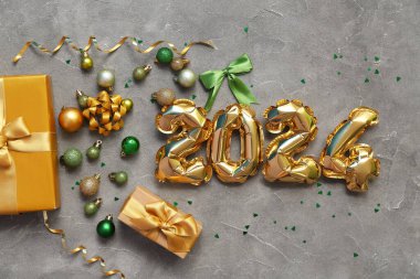 Şekil 2024 Noel süsleri ve gri arka planda hediye kutuları olan balonlardan yapılmıştır.