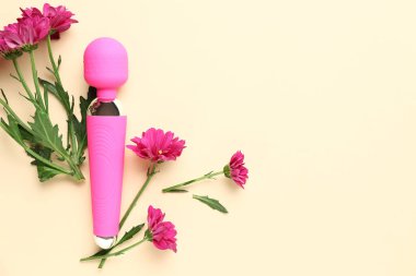 Seks dükkanından pembe vibratör ve bej arka planda güzel kasımpatı çiçekleri.