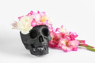 Beyaz arka planda güzel gladiolus çiçekleri olan siyah insan kafatası