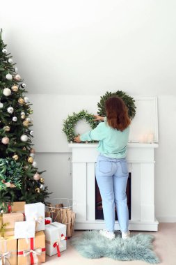 Kadın, Noel çelenkleriyle şenlikli oturma odasını dekore ediyor.