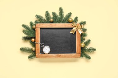 Cep saati ve sarı arka planda Noel ağacı dalları olan kadife tahtası.