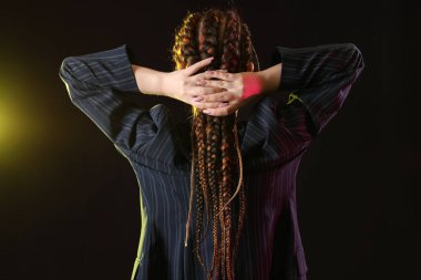 Koyu arka planda rastalı saçları olan genç bir kadın.