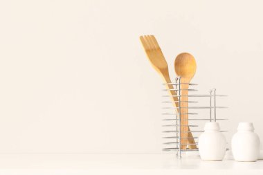 Mutfak gereçleri beyaz duvarın yanındaki masada.