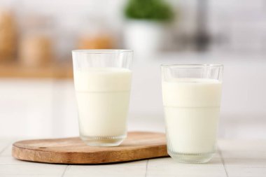 Tahta tahta tahta tahta, beyaz fayans masasında taze süt bardakları.