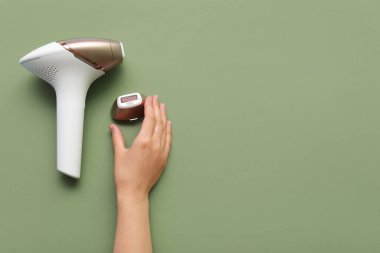 Yeşil arka planda modern fotoepilatör eklentisi olan kadın elleri