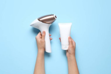 Modern fotokopi makinesi ve mavi arka planda bir şişe kozmetik ürünü olan kadın elleri.