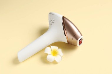 Soluk sarı arka planda güzel çiçekli modern fotoepilatör.