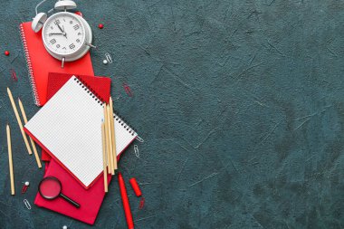 Koyu renk arkaplan üzerinde farklı kırtasiye ve alarm saatine sahip kompozisyon