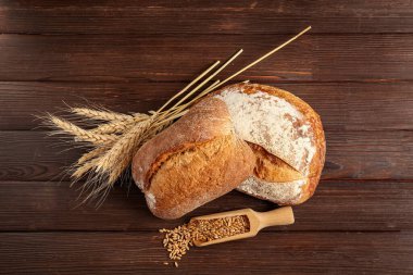 Somunlar taze ekmek, buğday dikenleri ve tahıllar ahşap arka planda