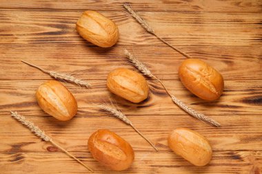 Tahta arka planda taze ekmek ve buğday dikenleri