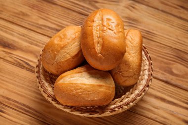 Tahta arka planda taze ekmek somunlarıyla dolu bir sepet.