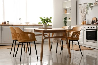 Beyaz tezgahlı ve yemek masalı aydınlık mutfağın içi.