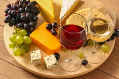 Lezzetli peynirli, üzümlü ve ahşap arka planda bir bardak şaraplı tahta.