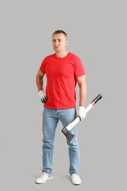 Gri arka planda baltası olan yetişkin oduncunun portresi