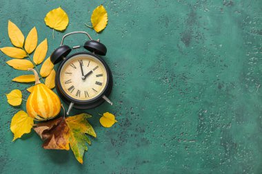 Sonbahar yapraklı çalar saat ve yeşil arka planda balkabağı