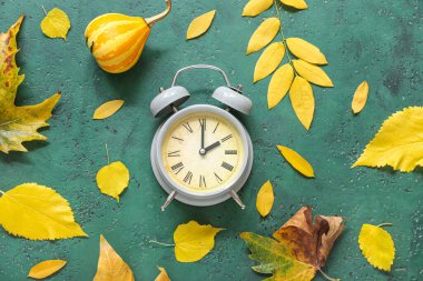 Sonbahar yapraklı çalar saat ve yeşil arka planda balkabağı