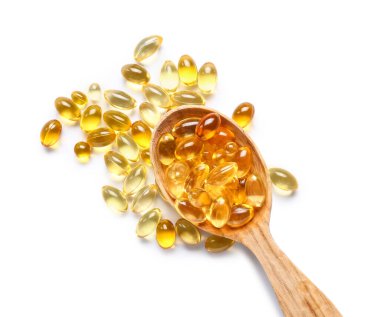 Beyaz arka planda balık yağı haplı ahşap kaşık.