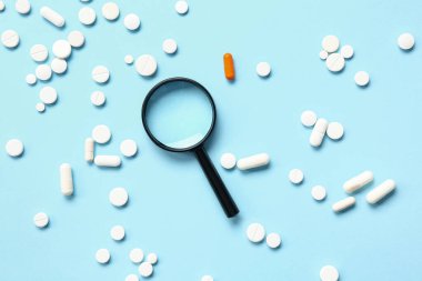 Büyüteç ve mavi arka planda bir sürü farklı hap.