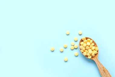 Mavi arka planda sarı haplı ahşap kaşık.